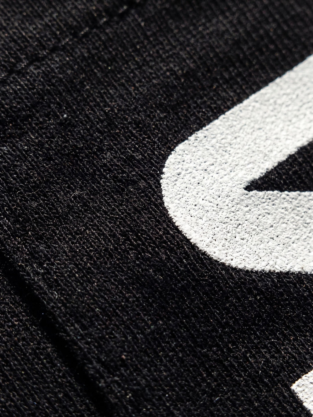 Close-up of the white shield graphic printed on the black Diamond Tuna Pocket Tee