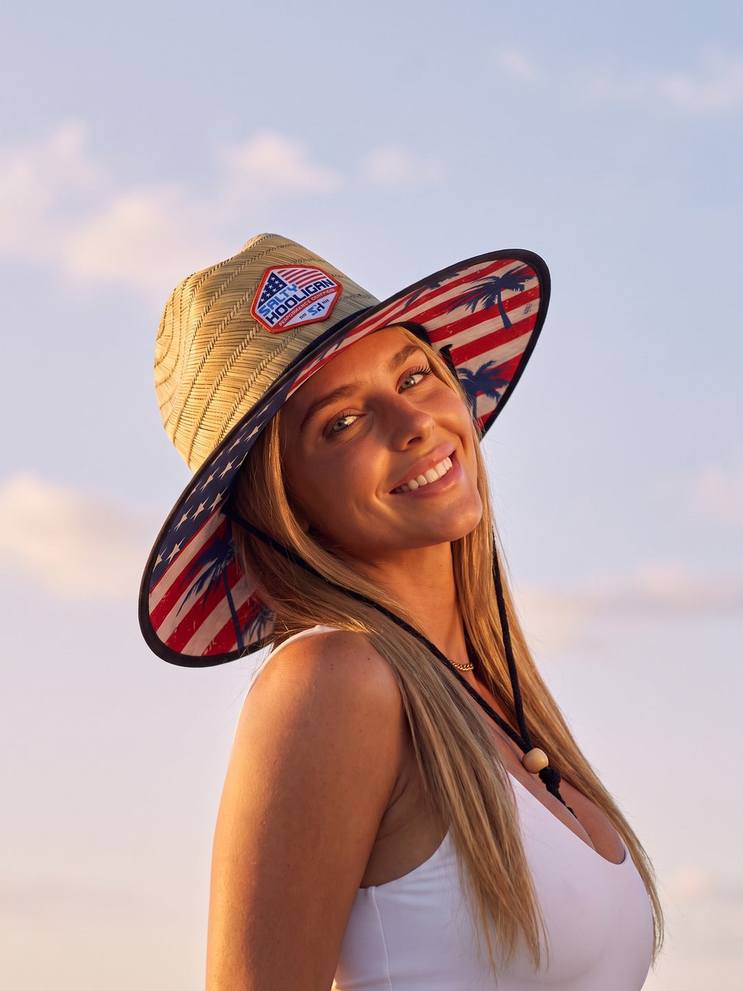 Smiling woman wearing the Flag Straw Hat with its stars-and-stripes underbrim
