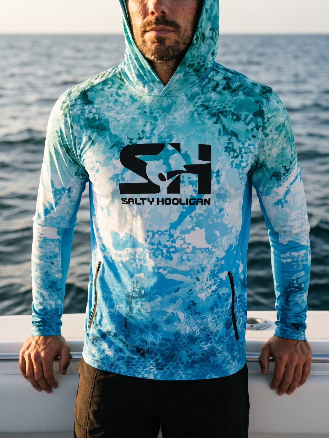 Man wearing the Ocean Pro Tech Hoodie at the rail of a boat offshore, chest logo in front