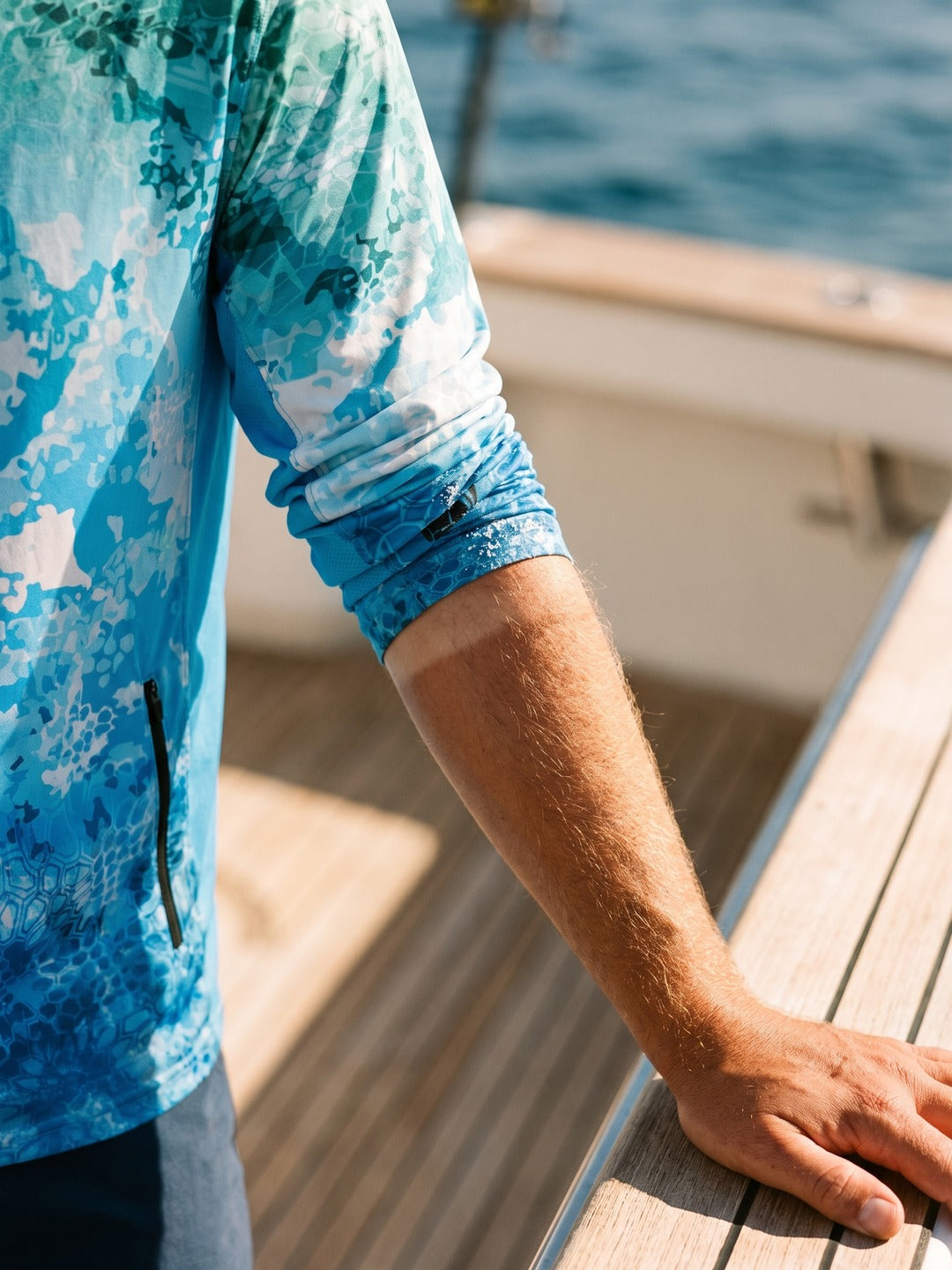Ocean Pro Tech Hoodie sleeve pushed up a forearm resting on a boat rail
