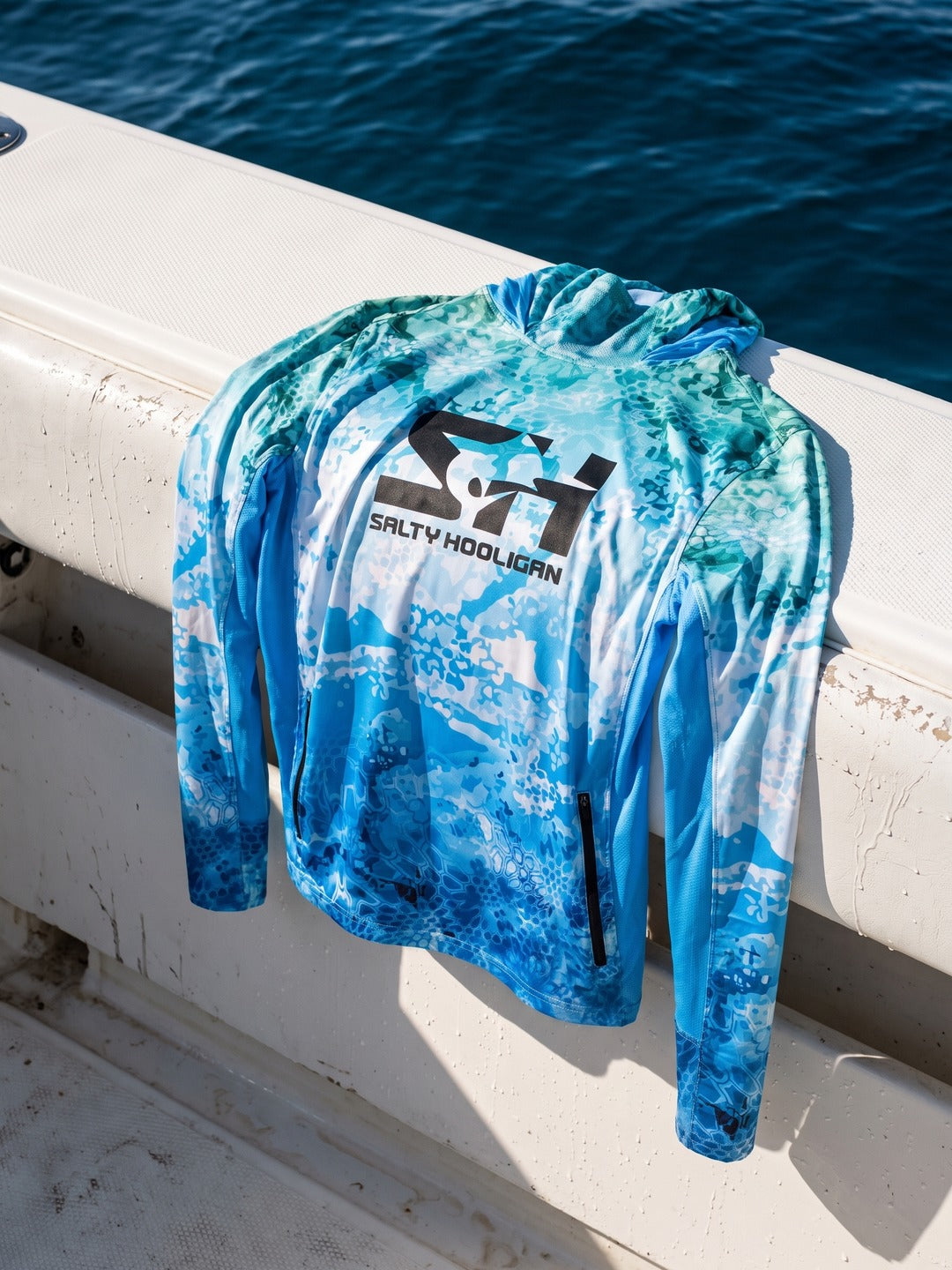 Ocean Pro Tech Hoodie laid over the white gunwale of a boat in the sun