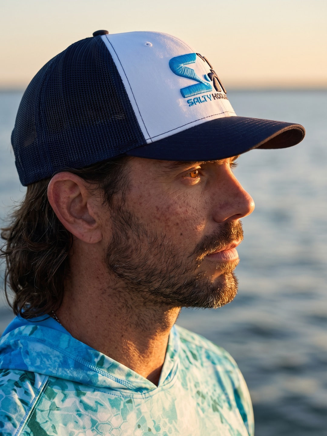 Man wearing the White/Navy Stitch Logo Trucker on the water, side view