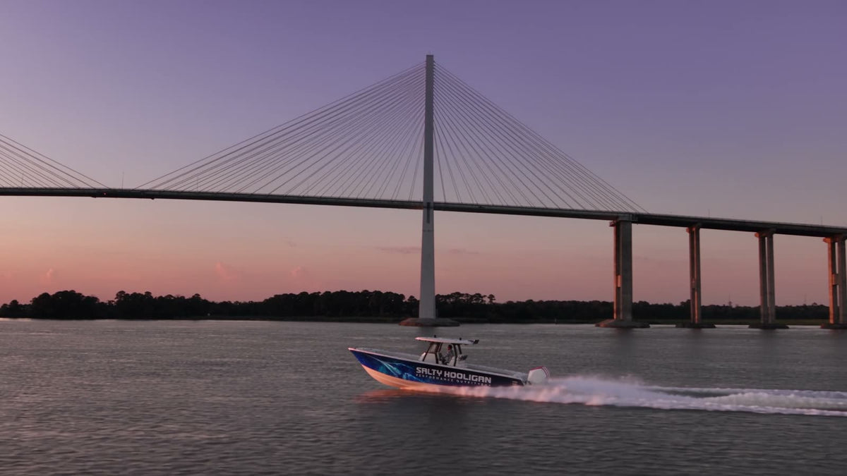 The Salty Hooligan boat running under the Sidney Lanier Bridge at sunset